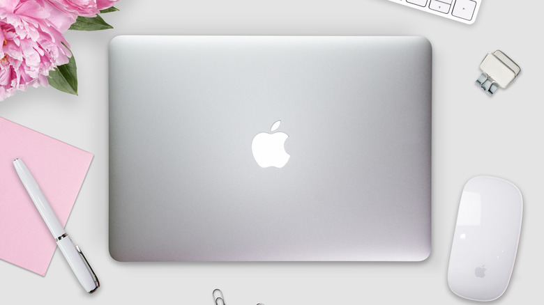 An Apple Macbook Pro on a desk with a Magic Mouse and stationery