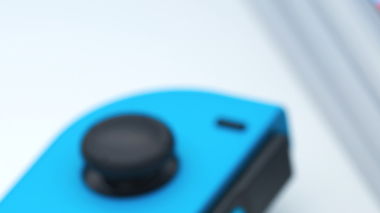 A Nintendo Switch console with detached joy-cons lying near a stack of Nintendo Switch game boxes