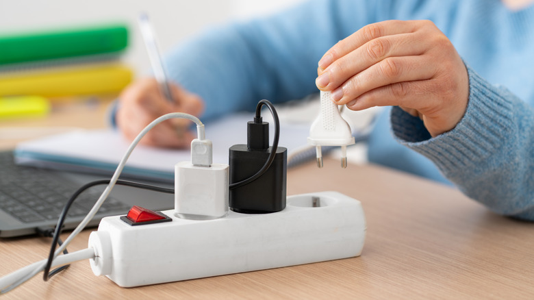 a person plugging in a laptop on a desk