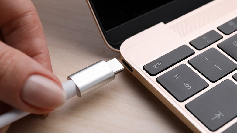 a hand plugging in a laptop