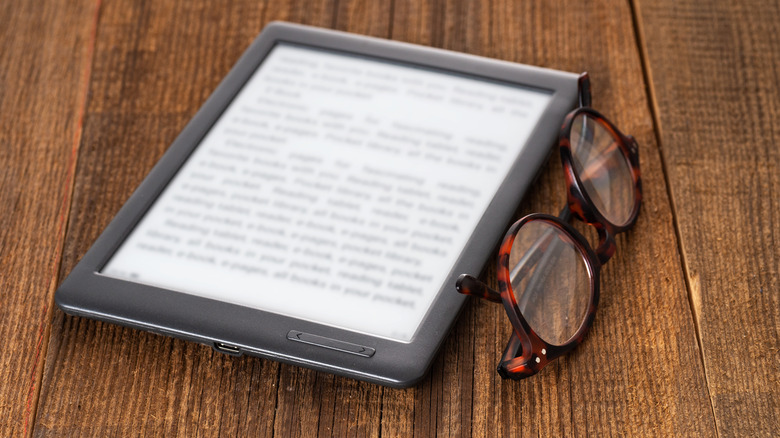 e-reader on a table with glasses next to it