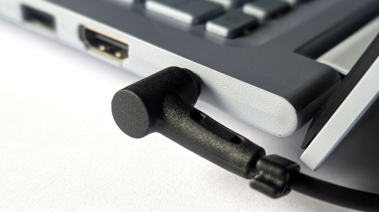 Close up of a proprietary power plug connected to a laptop's charging port.