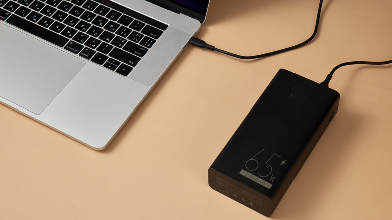 A laptop beside its charging adaptor.