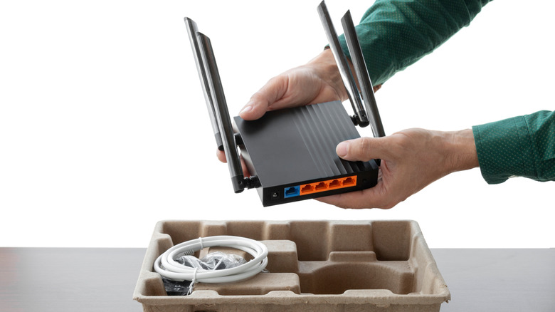 A person taking a new router with four antennas out of its packaging