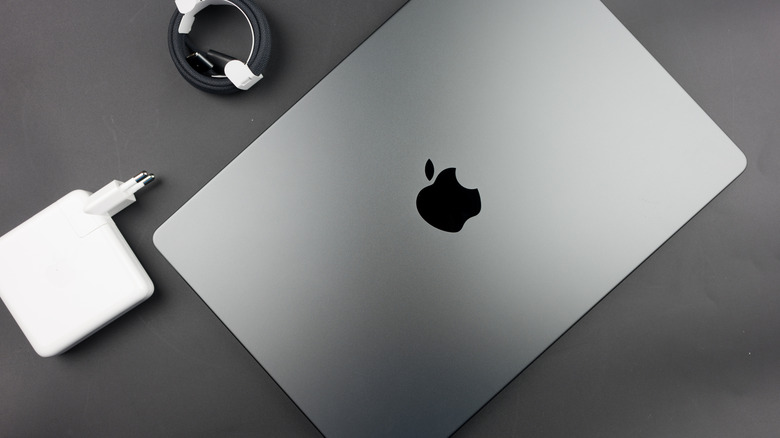 A MacBook, charger, and MagSafe cable on a desk.