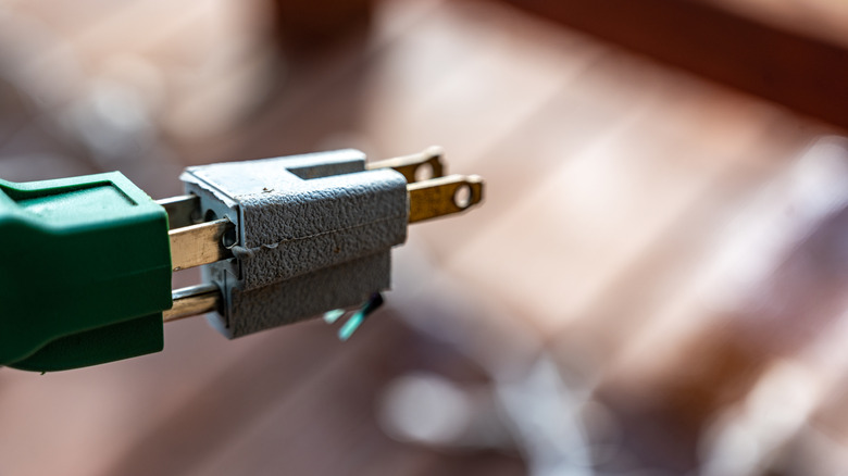 A three pong power connector being plugged into a two prong power connector adaptor