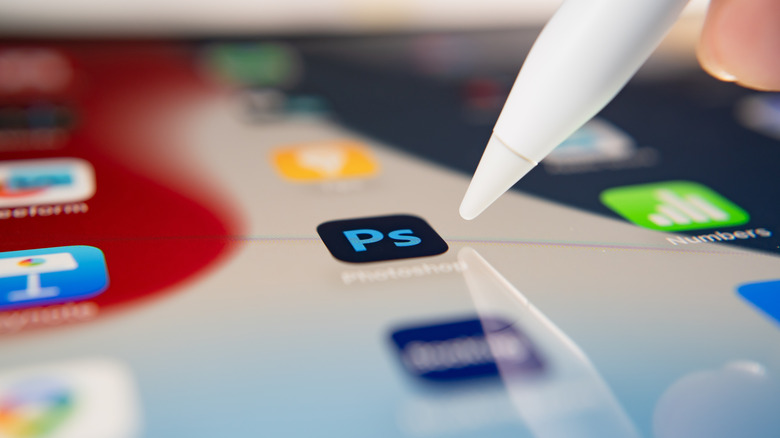 iPad user touching on an Adobe Photoshop icon to open the app.