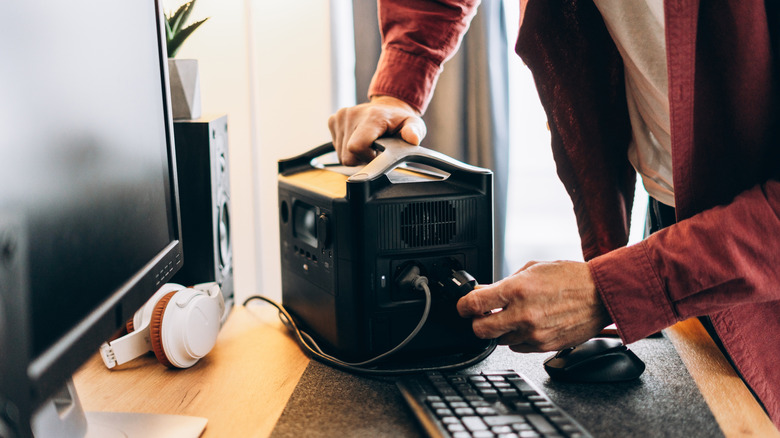 A man plugging his PC cables into a UPS