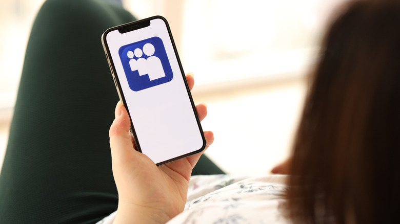 a woman holding up a phone with the Myspace logo