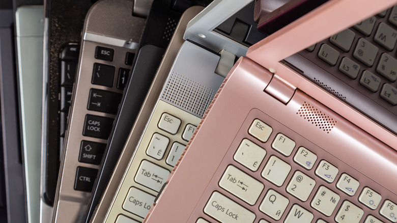 An assortment of different colored laptops stacked on top of each other.
