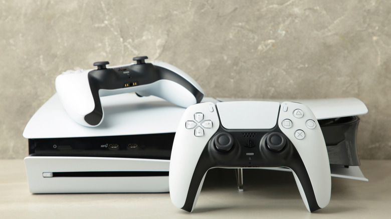 a white playstation 5 disc console with two dualsense controllers