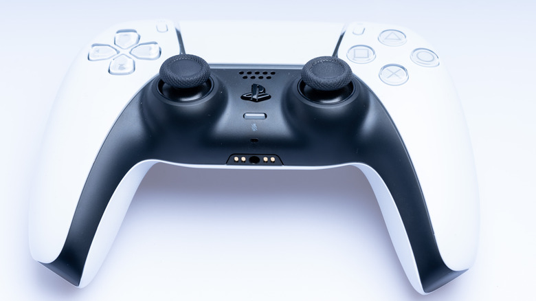 A PlayStation 5 DualSense controller lying on a white surface.