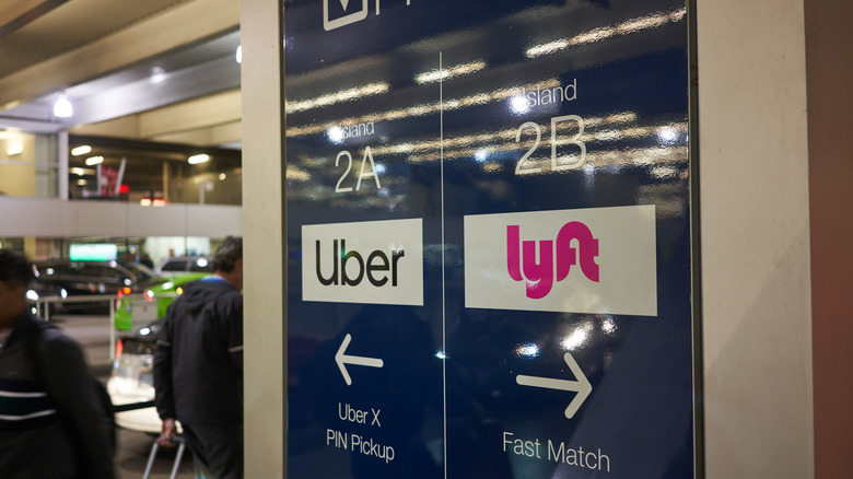 Uber and Lyft pickup signs near an airport entrance.