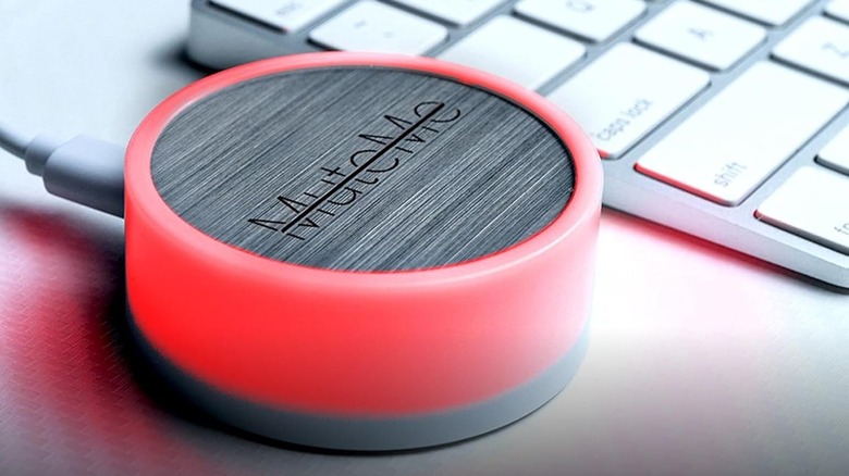 The original MuteMe set up and glowing red next to a laptop