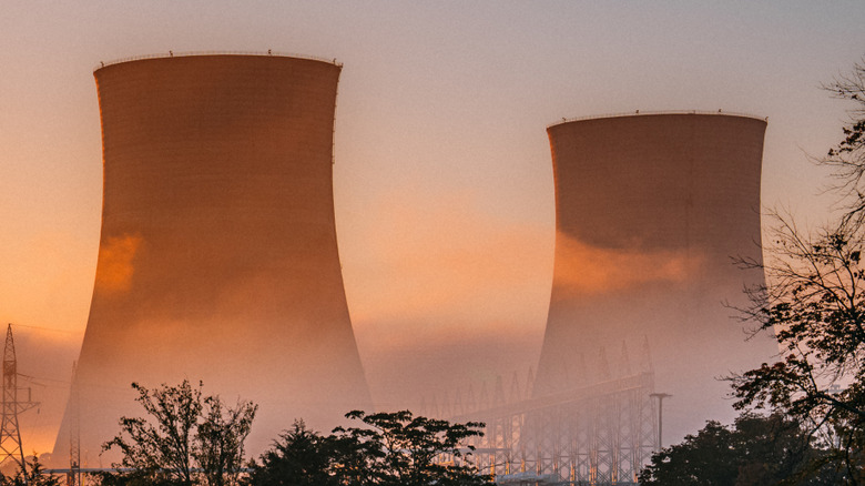 Two cooling towers of a nuclear facility standing with the sun setting
