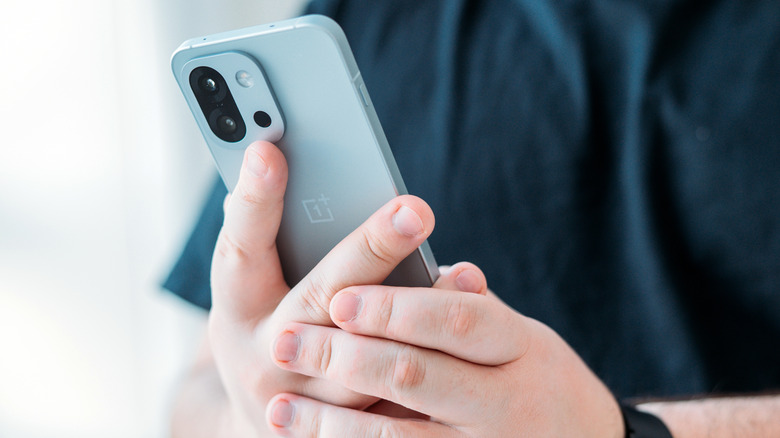 a person holding a OnePlus 13S and 13T in hand