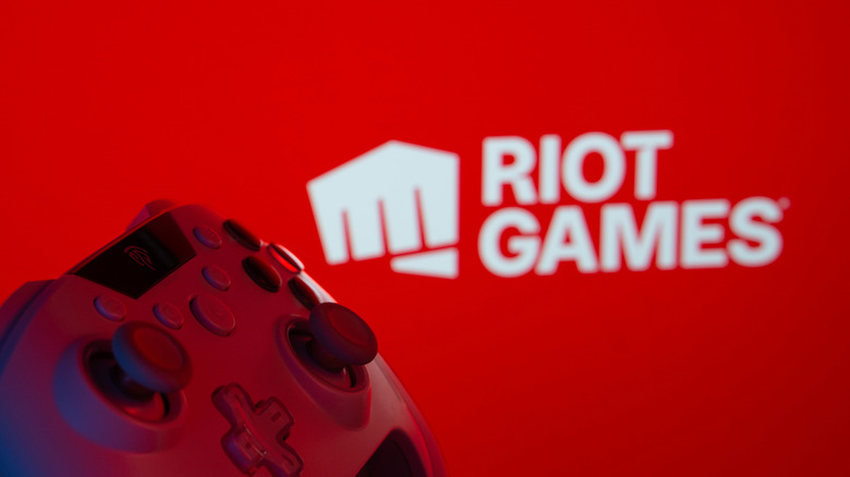 Photo of a controller with a Riot Games logo in the background.