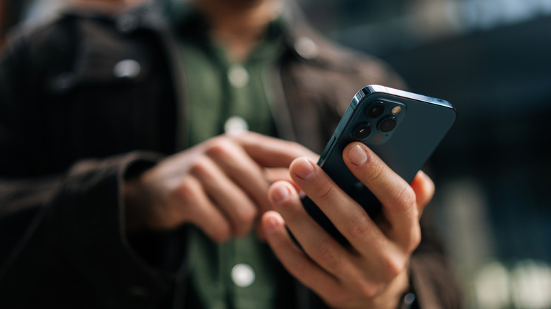 A person holding an iPhone and tapping on its screen