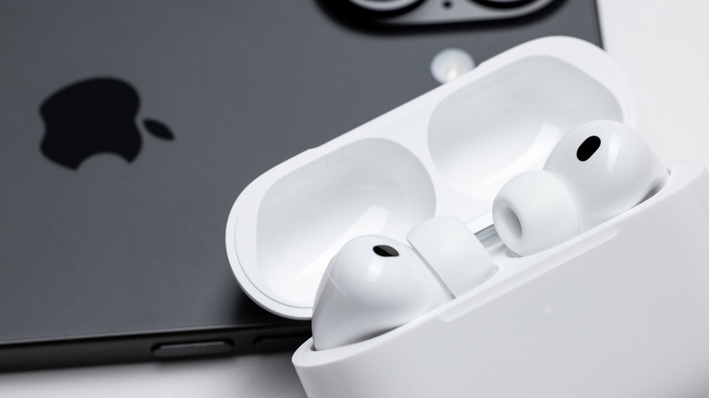 Apple AirPods in a charging case in front of an Apple iPhone