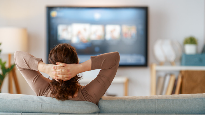 a woman lounging on her couch and watching TV