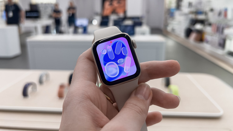 A person looking at a Apple Watch SE 3 model in an Apple retail store.