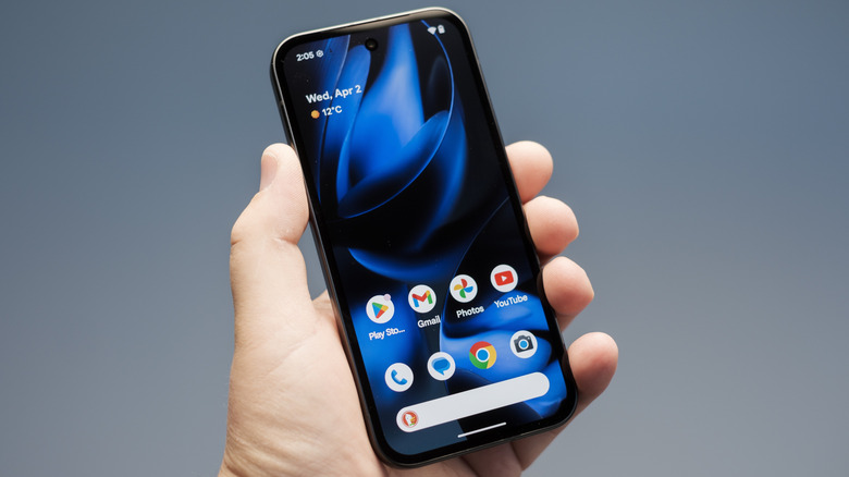 Person holding a Google Pixel 9a smartphone with the display showing the Andorid OS