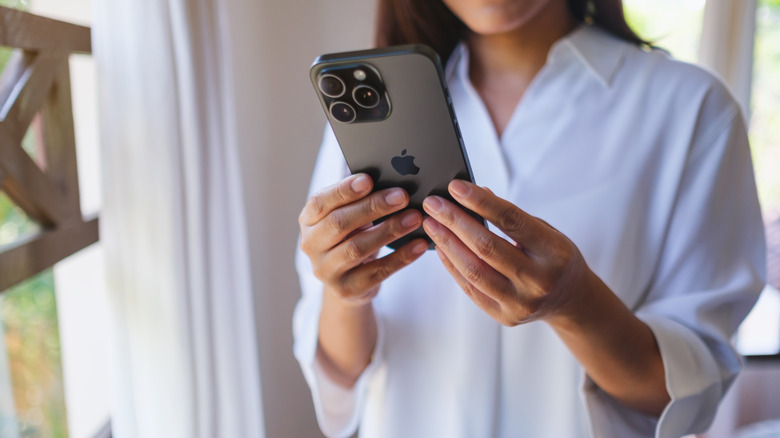 A woman holding the iPhone 15 Pro Max phone.