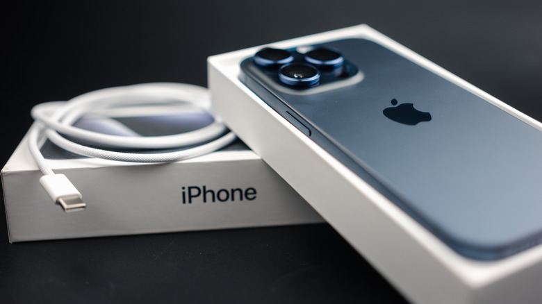 An iPhone 15 in a box with a USB-C cable beside it.