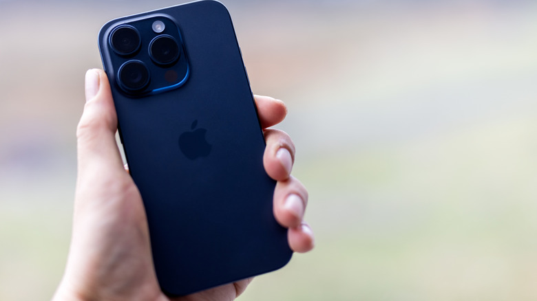 A hand holding the iPhone 15 Pro in blue.