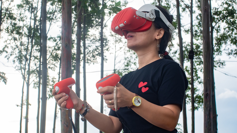 Woman using a red Meta Quest 2 headset outdoors