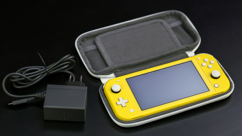 A yellow Nintendo Switch Lite in a case and a charger besides it