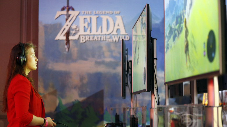 a woman playing The Legend of Zelda: Breath of the Wild on the Nintendo Switch