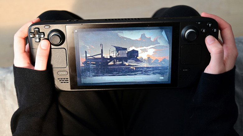 a person holding a Steam Deck while showing a game on the display