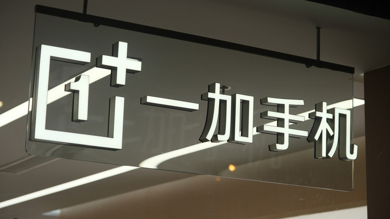 A large, lit-up sign fronting a OnePlus retail space in China.