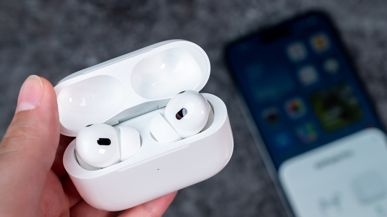 open airpods case with iphone blurred in background