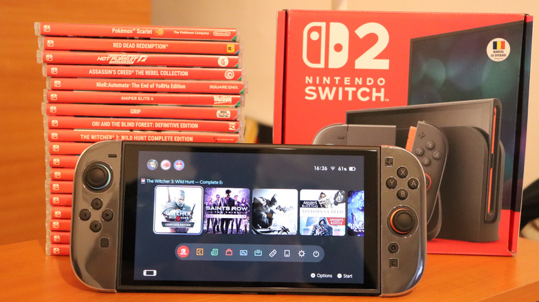 Nintendo Switch 2 next to retail box and a stack of Nintendo Switch 1 boxed titles