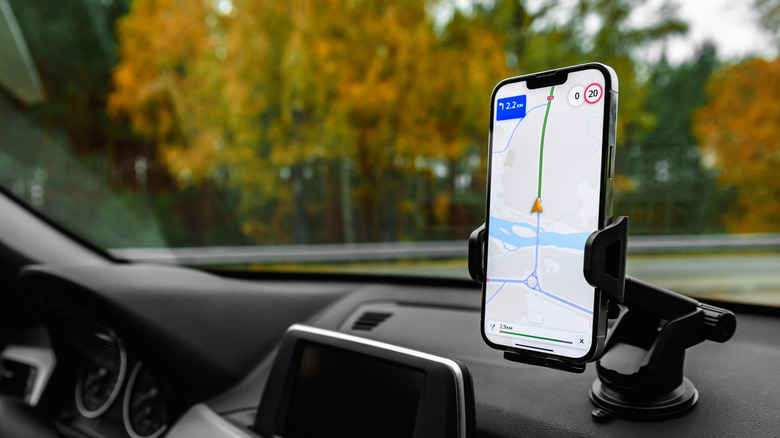 A phone being held on a phone mount, attached inside a car in front of the windshield