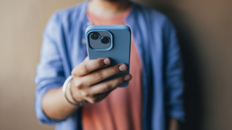 A person using an iPhone to take a selfie.