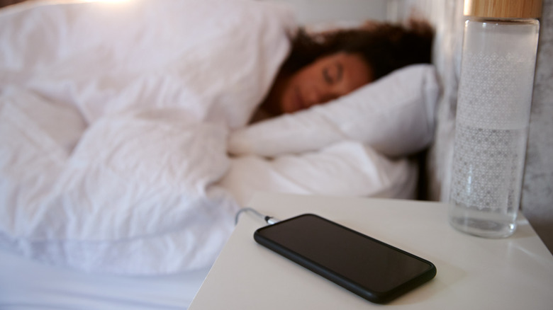 Woman sleeps with phone on the nightstand