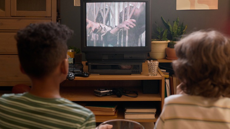 Two kids watch an older CRT-style TV.