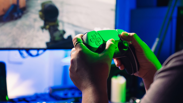 A person  holding a PS5 controller while playing an FPS game