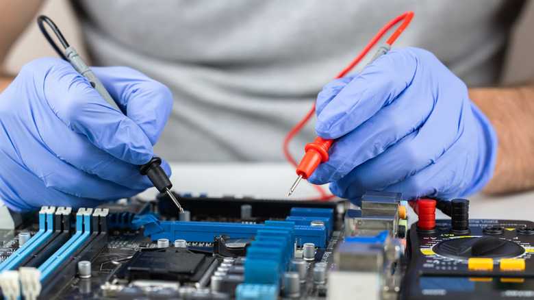 A person testing a motherboard with electrical probes
