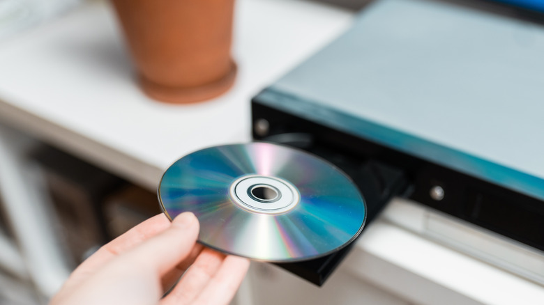 A hand putting a disc into a Blu-ray player