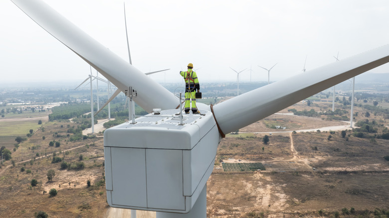 An engineer standing on top of a wind turbine, looking out over the countryside
