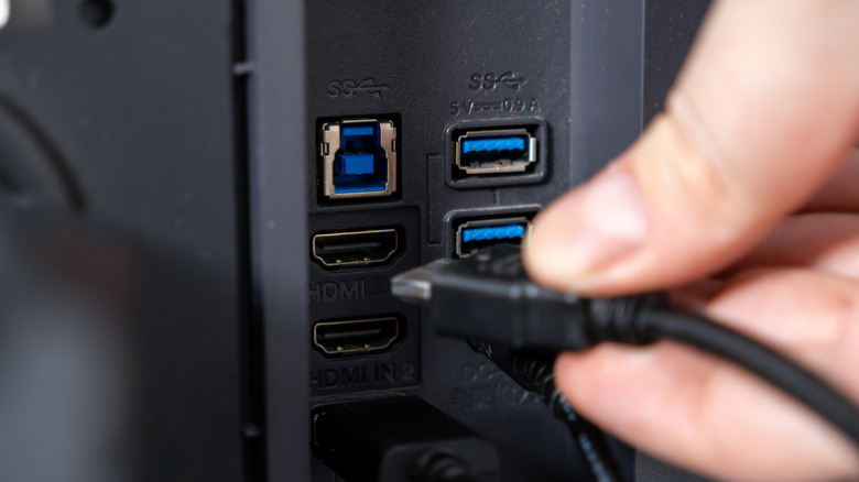 A person plugging in an HDMI cable.