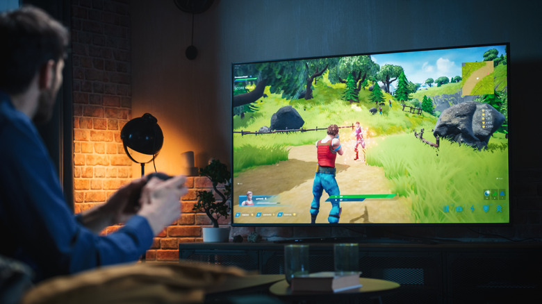 A man playing Fortnite on a living room TV.