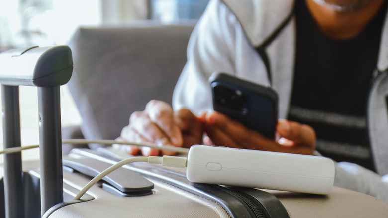 Person charging a phone at an airport lounge