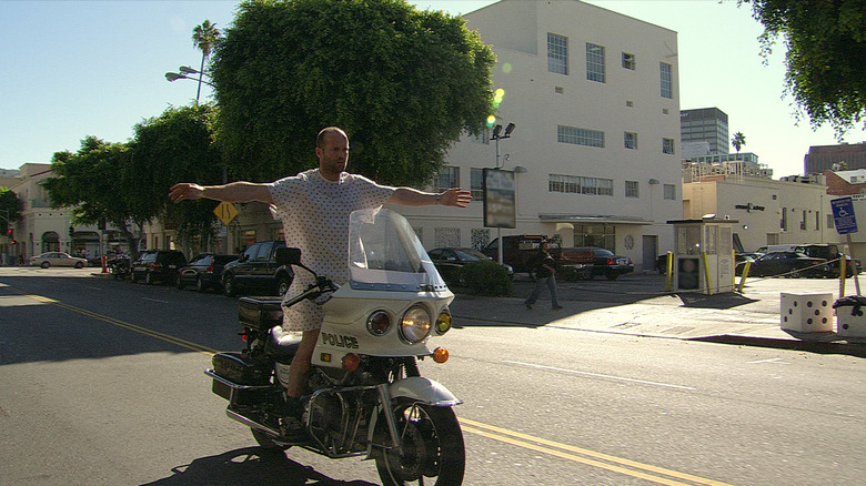 Chev Chelios riding a police bike in a hospital gown