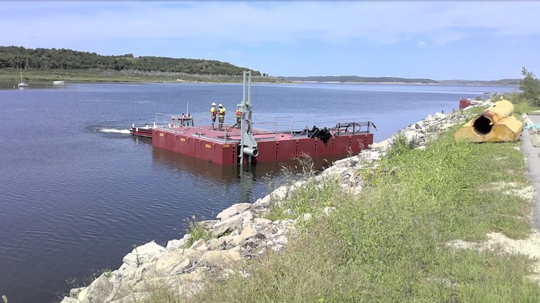 Barge on lake with workers standing on it