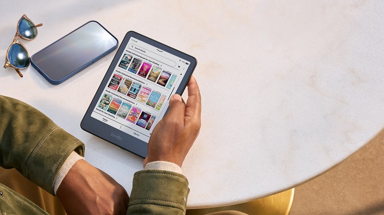 Person browsing a Kindle's ebook library while sitting at a table